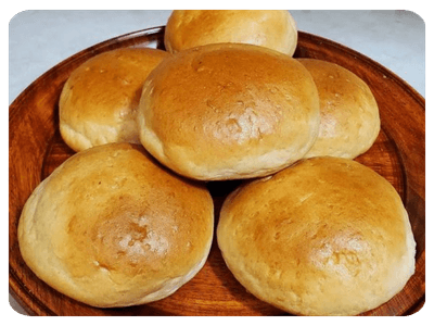 Pães redondos dourados em bandeja de madeira